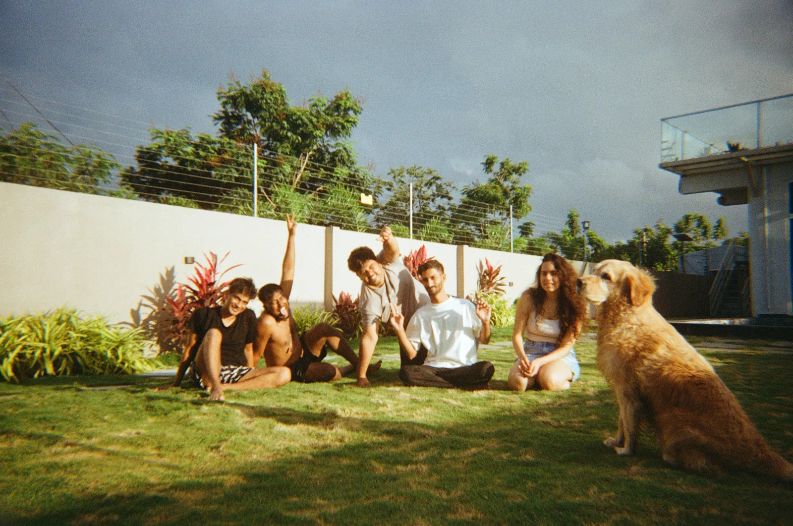 Two people crouching to meet a small dog in a garden