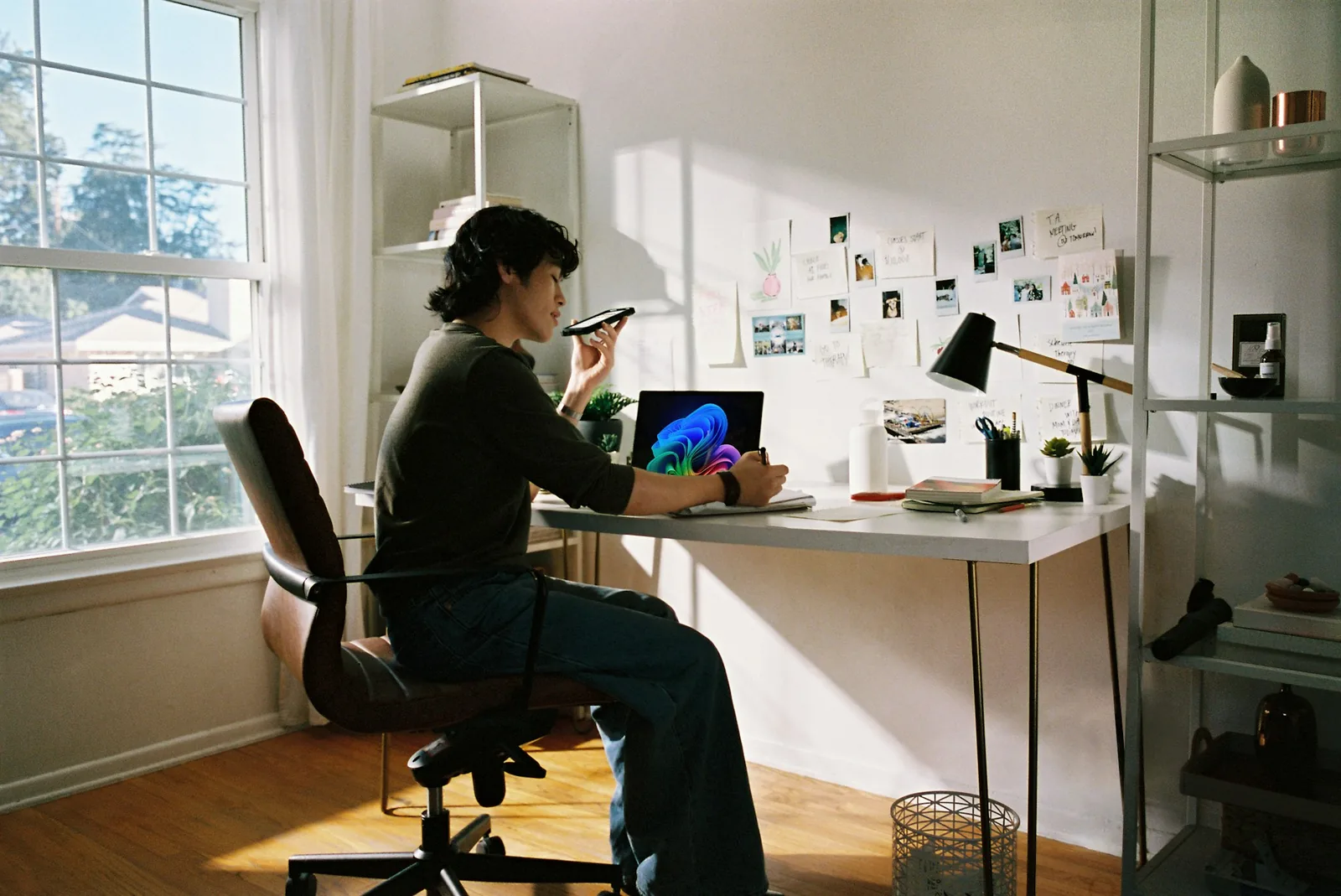 A person taking a phone call while sitting at a desk at home