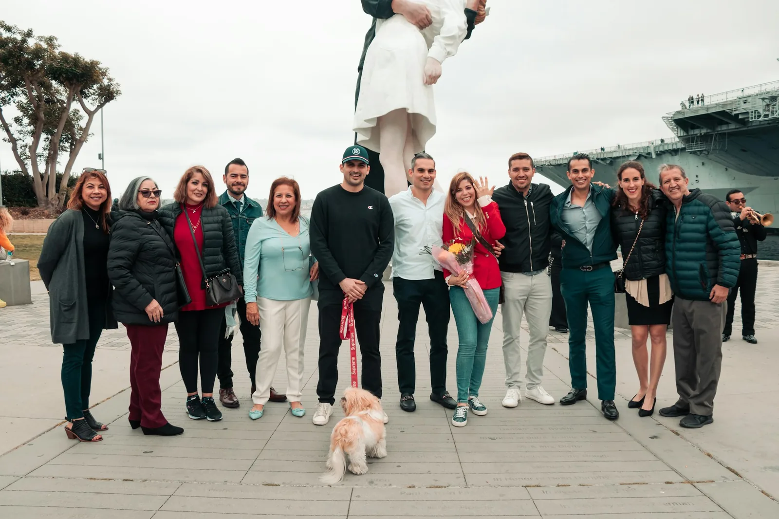 A group of people gathered around a small dog outdoors