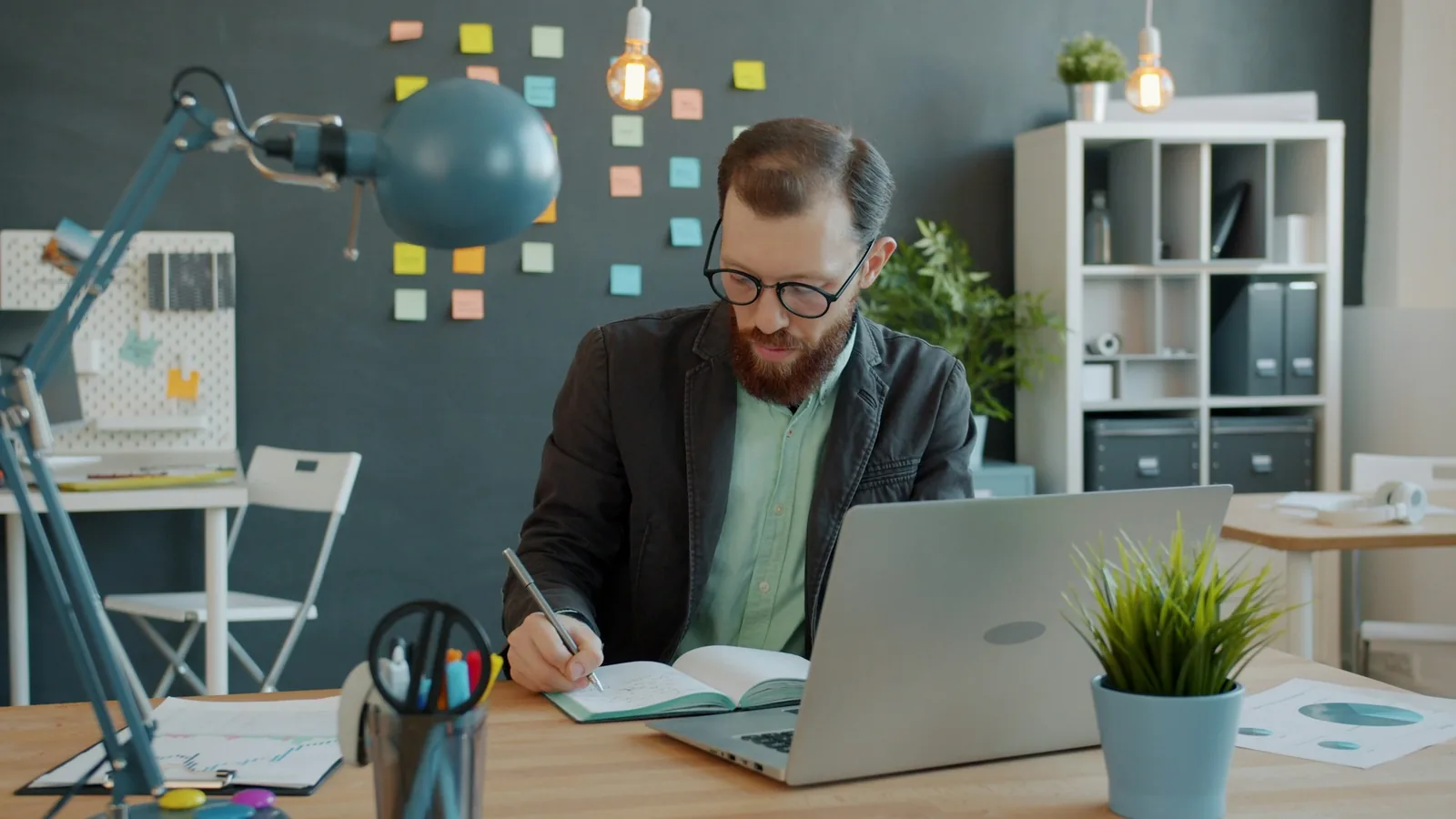 A person writing notes in a notebook at a desk