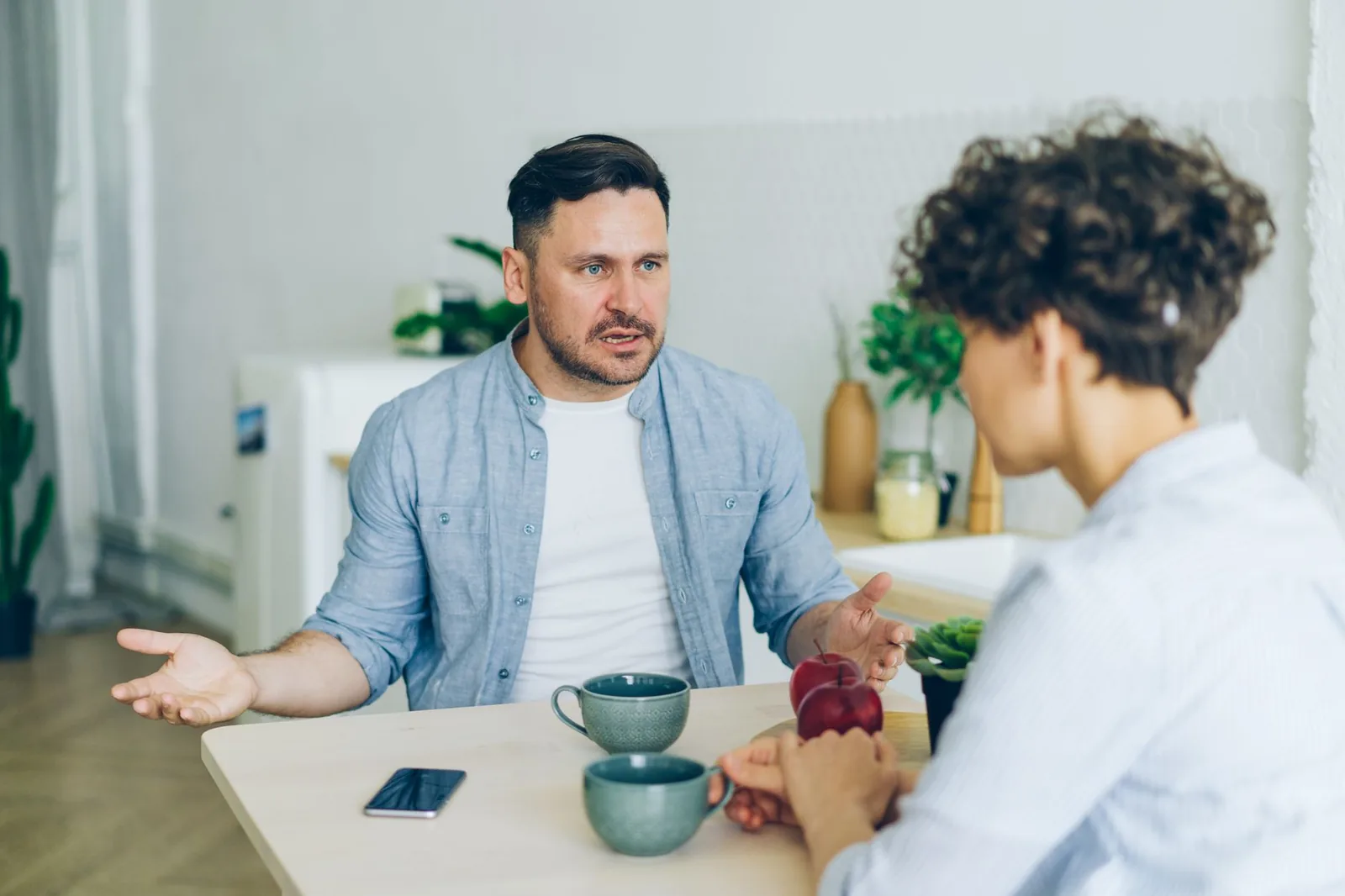 Two people talking at a kitchen table