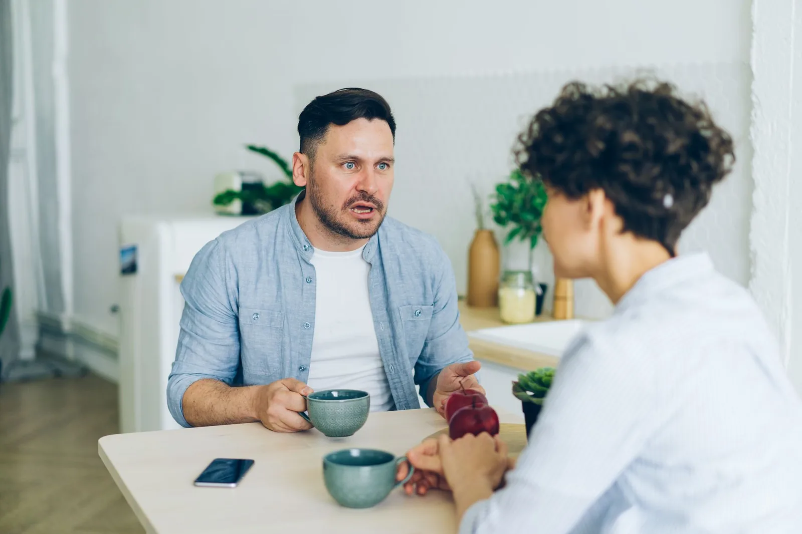 Two people talking at a kitchen table