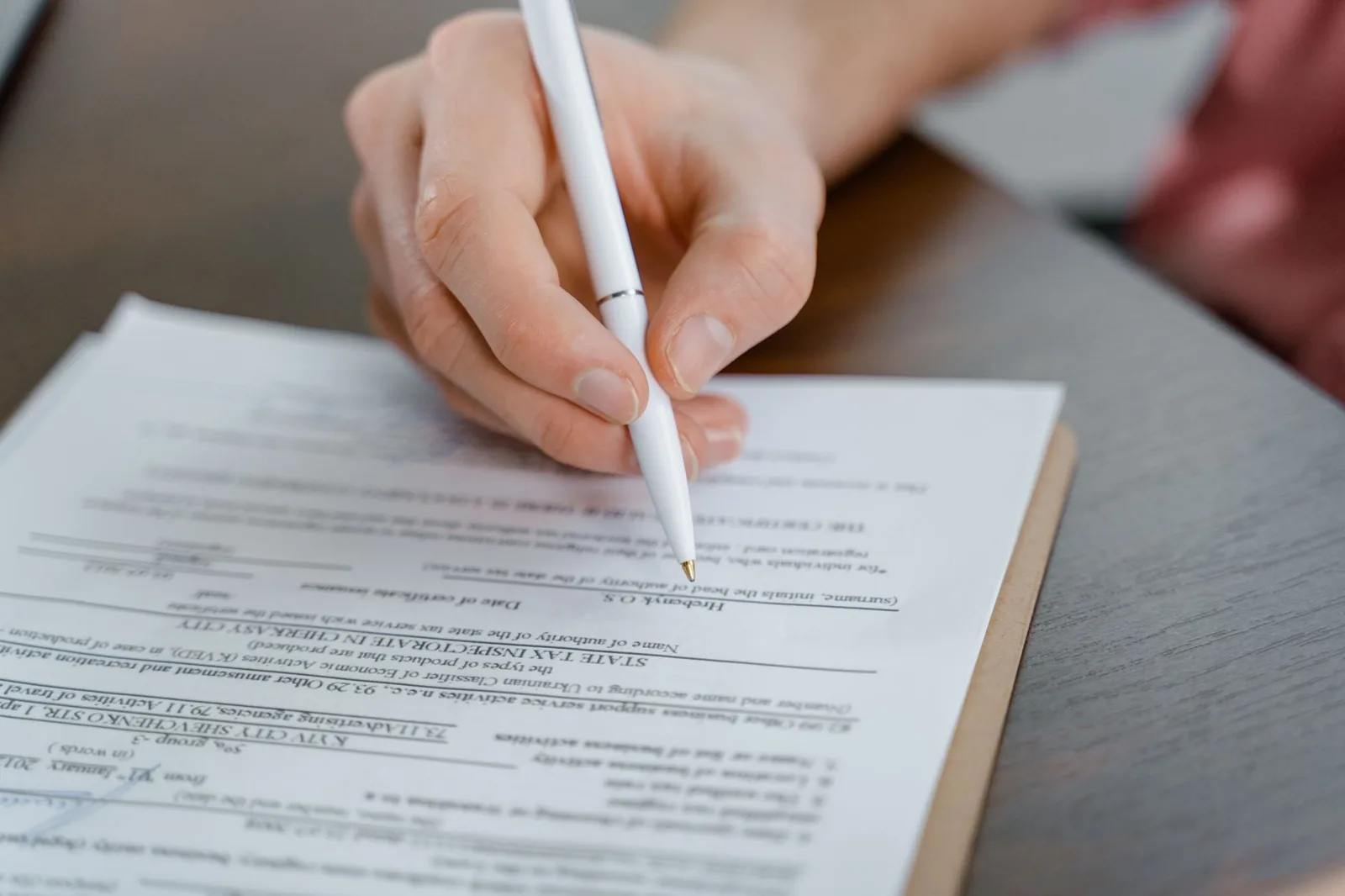 A person completing paperwork at a table at home
