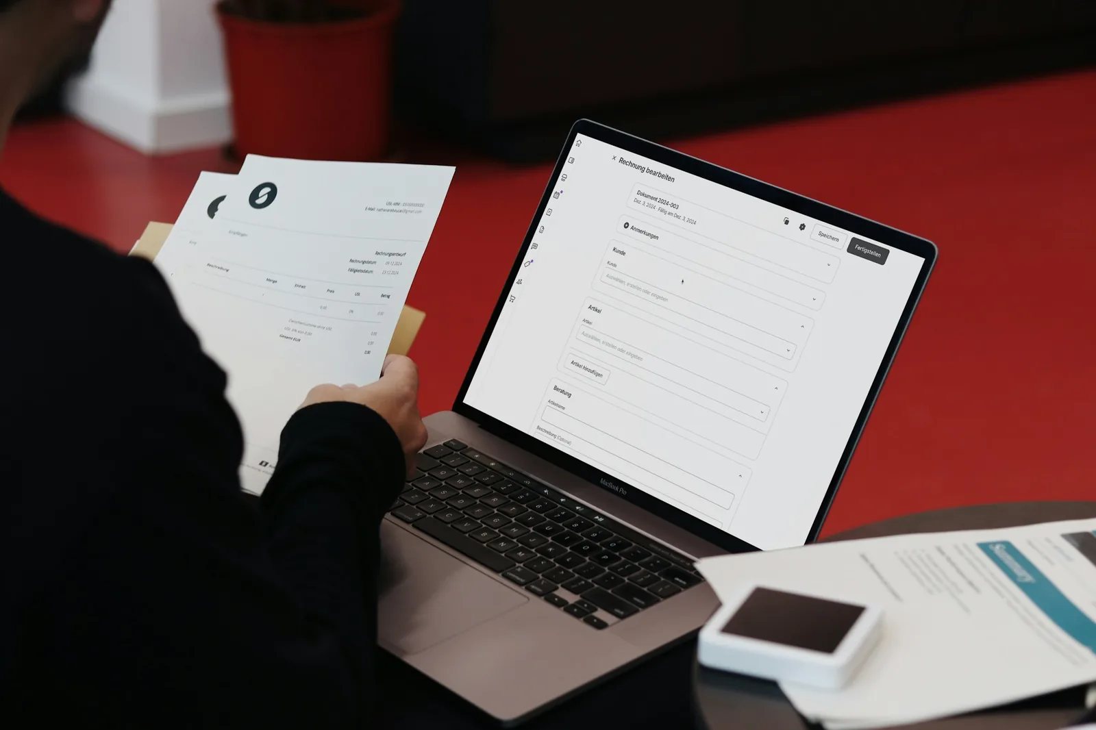 A person reviewing paperwork beside a laptop