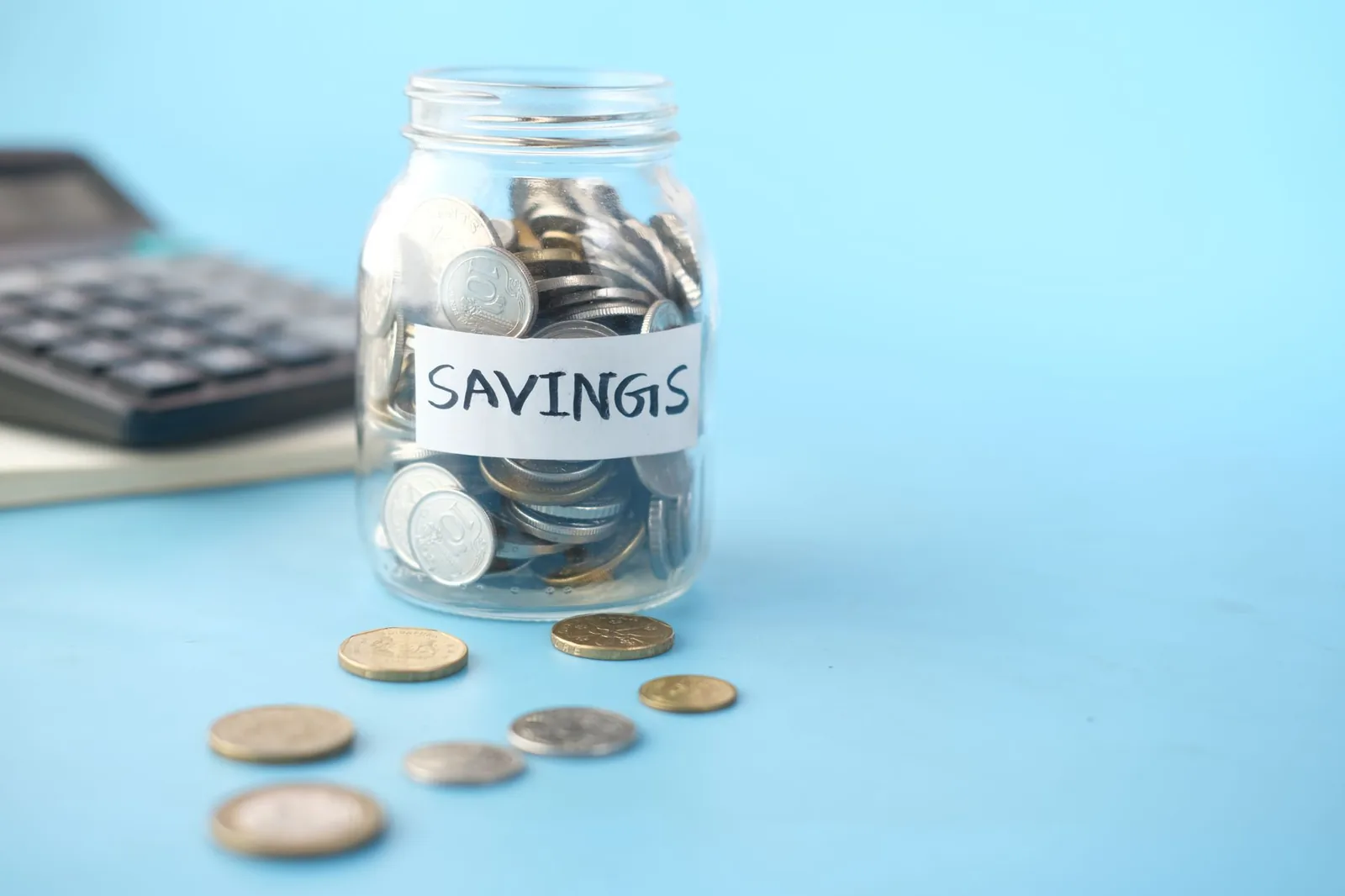 Coins beside a savings jar