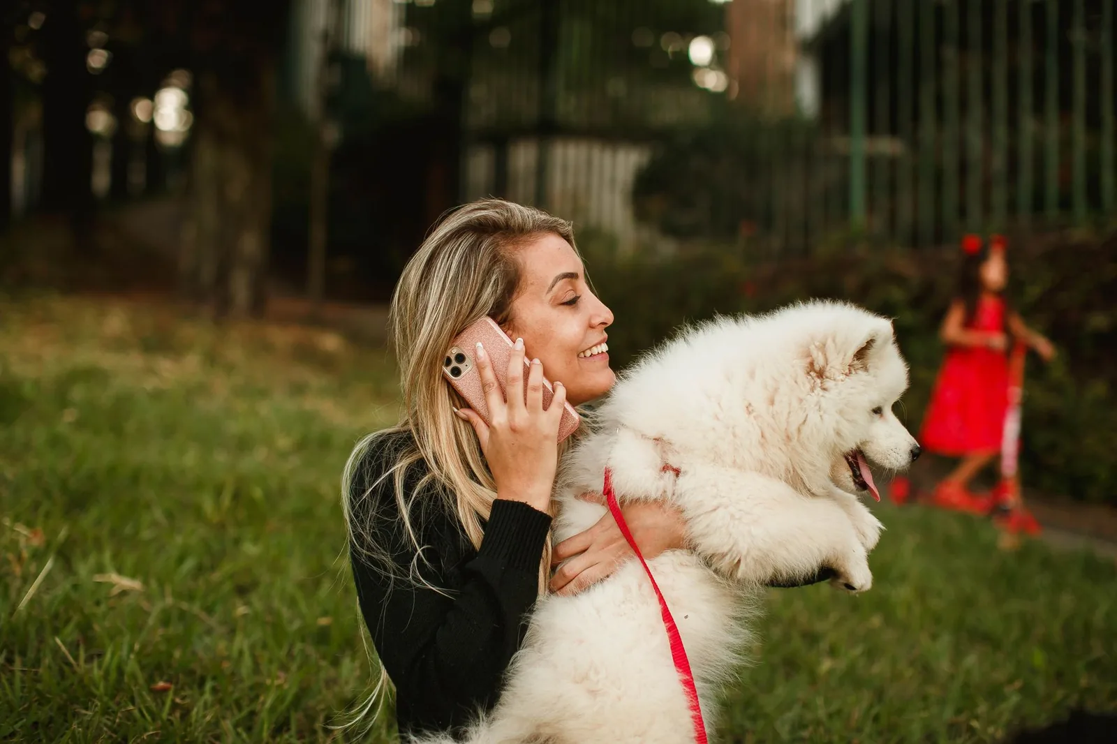 A person crouching and calling a dog outdoors